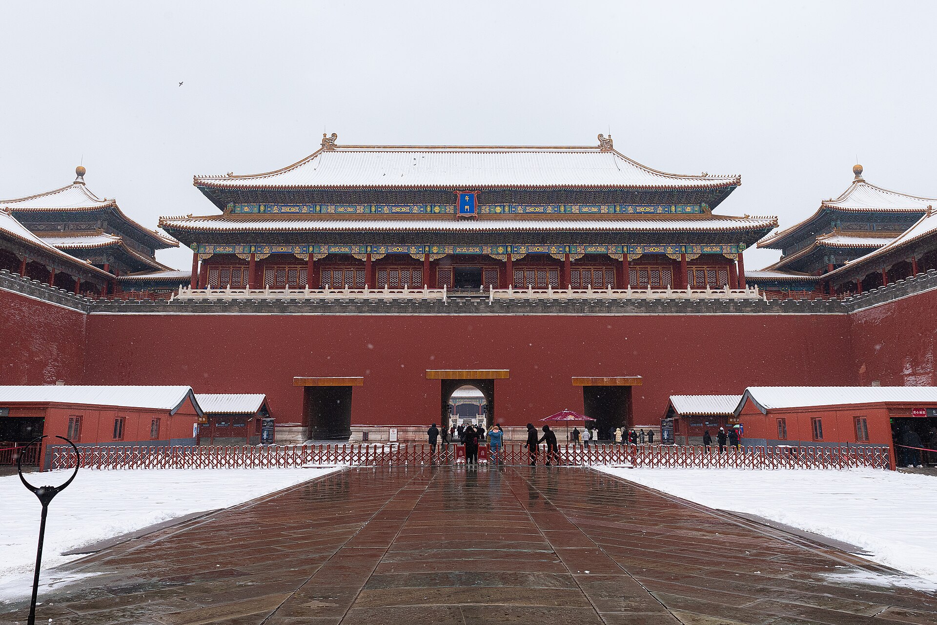 Meridian Gate at Beijing's Forbidden City after snowfall, with snow on the roofs and wet paving.