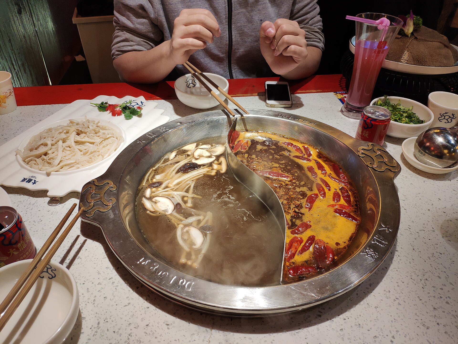 A divided yuanyang-style hotpot with light and red broths at a Chengdu table in January 2019.