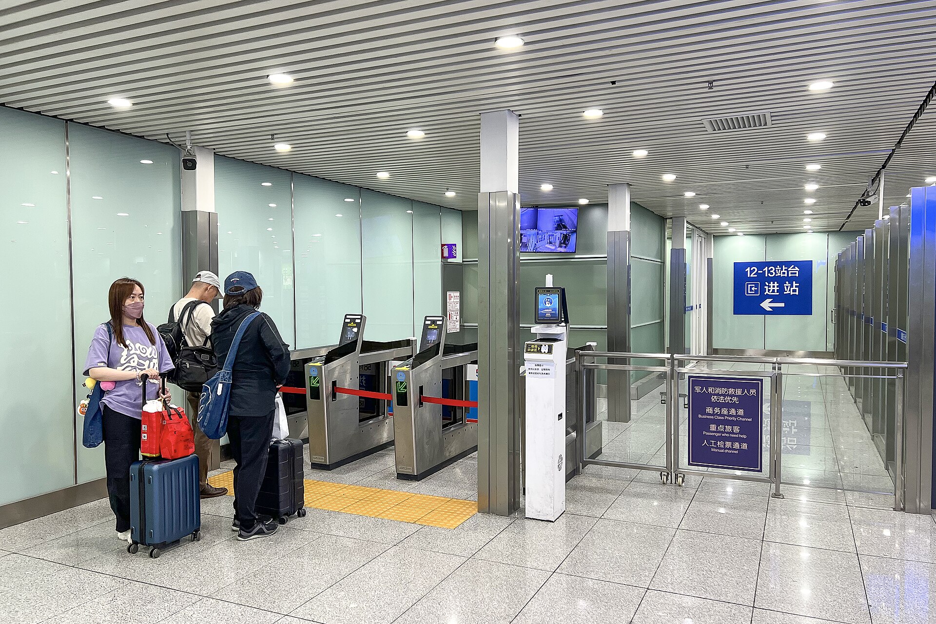 Automatic gates beside a bilingual manual-check-channel sign at Beijing South Railway Station in May 2026.