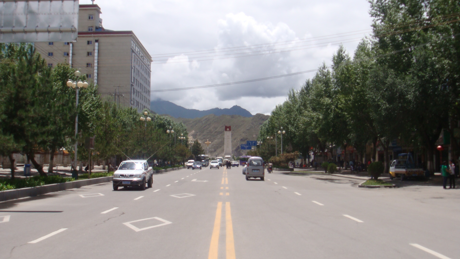 Traffic moves along a broad Lhasa street toward the Sichuan-Tibet and Qinghai-Tibet Highways Monument.