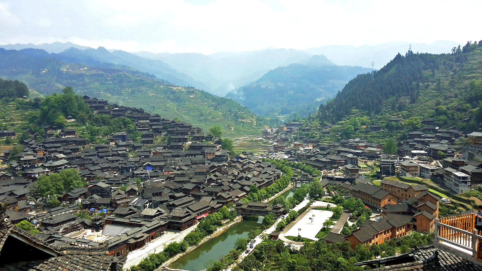 Dense dark-roofed buildings spread across the valley and hillsides at Xijiang village in Guizhou.
