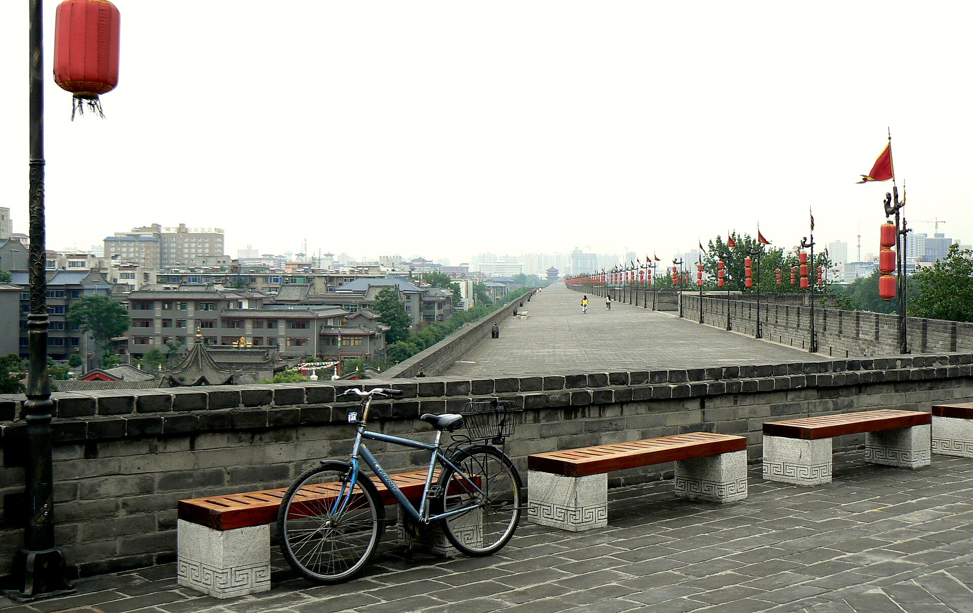 The broad top of Xi'an City Wall beside dense city buildings, with a bicycle in the foreground, in 2009.
