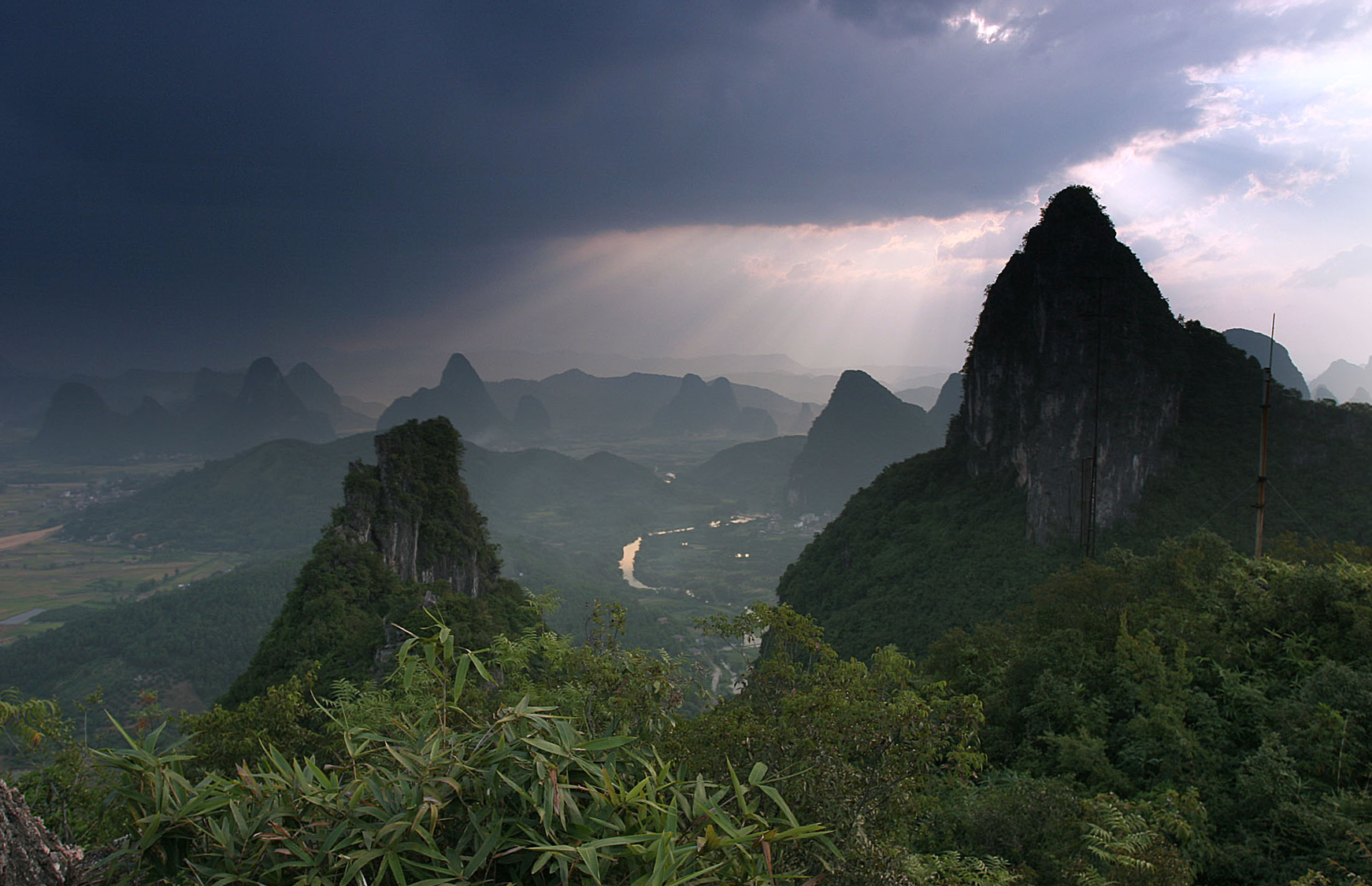 Karst peaks and countryside below Moon Hill outside Yangshuo beneath a dark rain cloud in 2007.