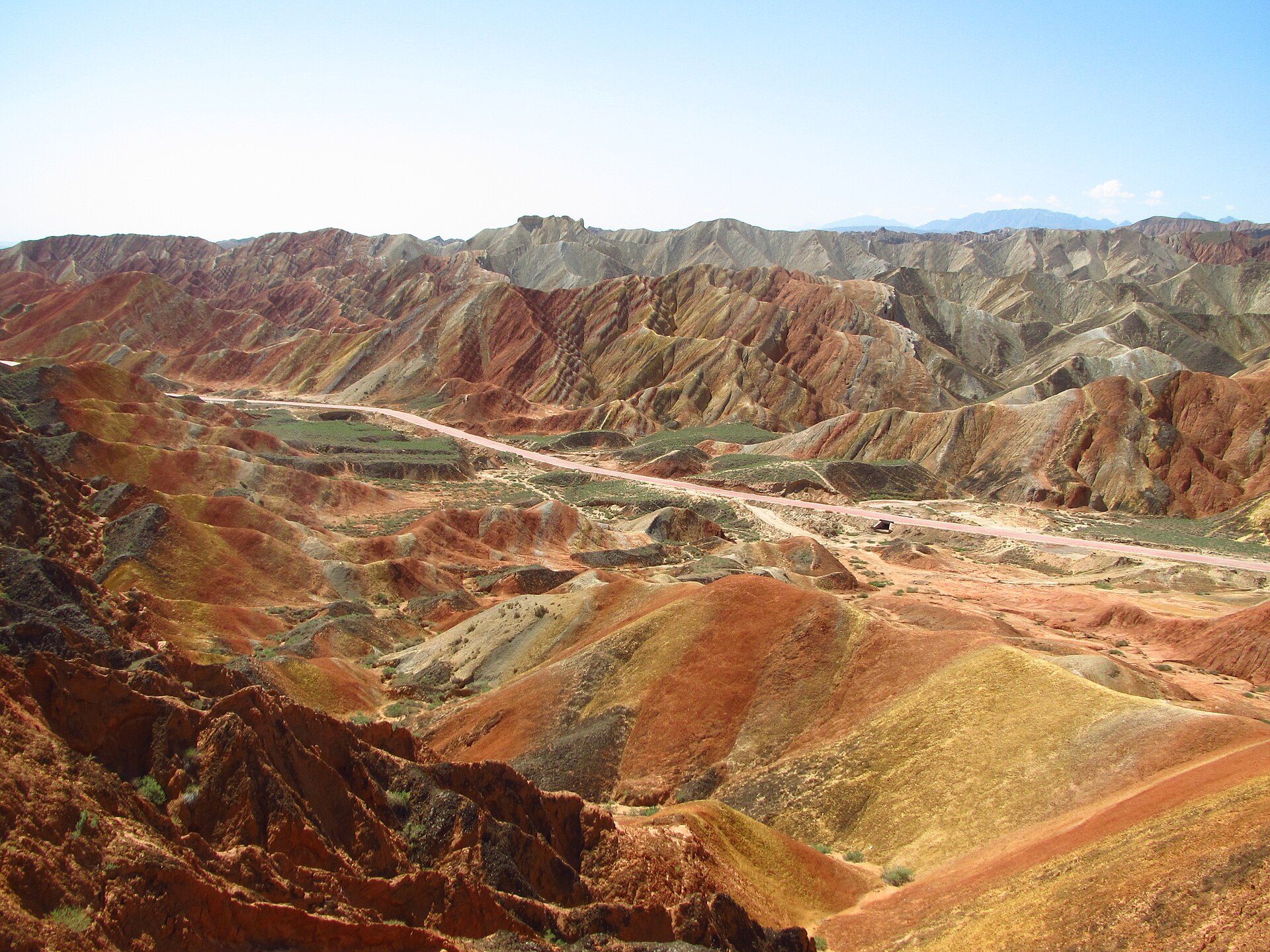 A broad paved road crosses layered hills inside Zhangye Danxia National Geological Park in July 2014.